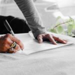 person writing on white paper on table