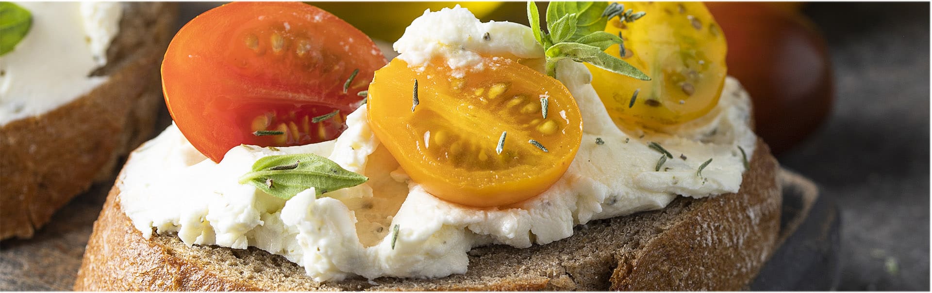 Close up of bruschetta with cream cheese and different tomato cherry  garnished with fresh basil leaves. Delicious starter